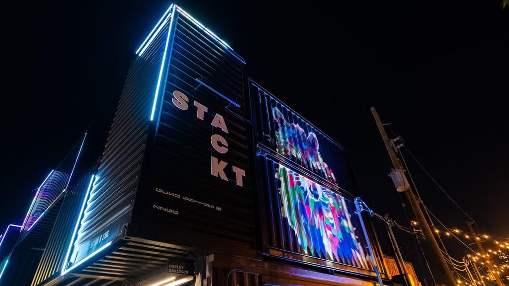 STACKT Market shipping containers lit with neon colours at night Open-air drinks, pop-ups and event nights